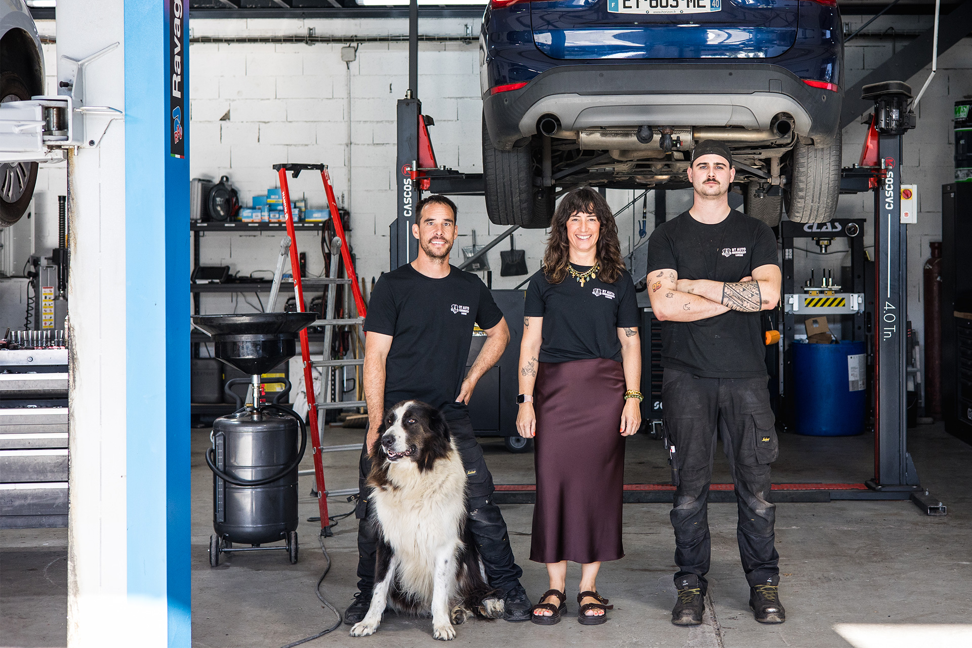 L'équipe RT Auto et son chien dans l'atelier, sous un véhicule sur pont élévateur