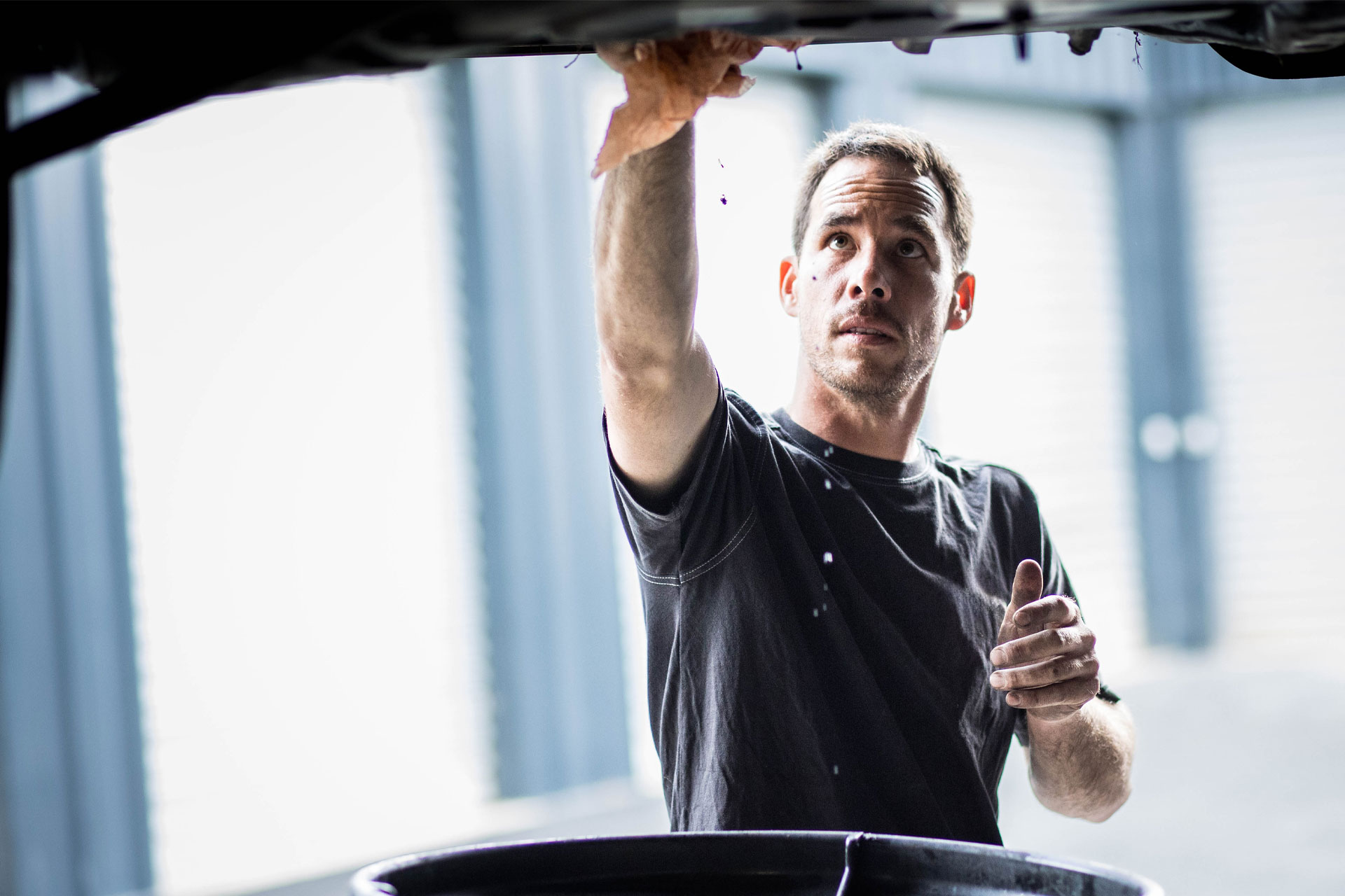 Régis travaillant sous un véhicule dans l'atelier RT Auto